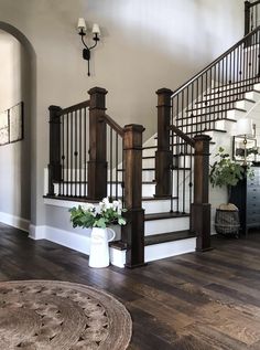 the stairs in this house are made of wood and wrought iron railings, along with potted plants