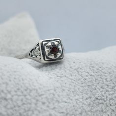 This vintage Joe Espisito ring is a stunning piece of jewelry that will make any occasion special. The ring is made of sterling silver and features a beautiful blood red garnet stone. The filigree design adds a touch of elegance to the ring, making it perfect for a formal event or a day at the beach. The ring is a size 5.25 and is signed by the artist. It is a unique piece that will make a great addition to any collection. Whether you are buying it as a gift or for yourself, this ring is sure to impress. Thank you for considering our merchandise! All items are described to the best of our knowledge. Vintage and antique pieces may show signs of wear consistent with their age.  Note there may be reflections, if any, from the camera or lights. Please look carefully at all the photos as they a Vintage Hallmarked White Gold Ruby Ring, Antique Sterling Silver Engraved Open Ring, Hallmarked Vintage White Gold Ruby Ring, Antique Engraved Open Ring In Sterling Silver, Vintage Red Hallmarked Signet Ring, Classic Garnet Signet Ring For Anniversary, Classic Sterling Silver Birthstone Ring With Gemstone, Vintage Sterling Silver Filigree Ring, Victorian Sterling Silver Filigree Ring Stamped 925