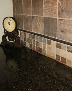 a clock sitting on top of a counter next to a tile backsplash in a kitchen