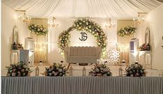 a decorated stage set up for a wedding ceremony with flowers and greenery on it