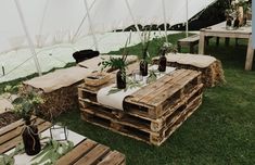 tables made out of wooden pallets are set up in the grass for an outdoor event