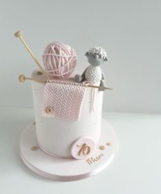 there is a small cake that has yarn in the basket on it and two balls of yarn