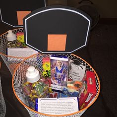 two baskets filled with items on top of a black tablecloth covered floor next to each other