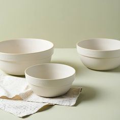 three white bowls sitting on top of a table next to napkins and paper towels