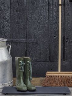 a pair of green boots sitting on top of a rug next to a metal watering can