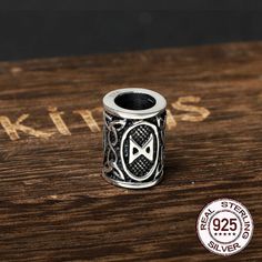 a silver bead with an emblem on it sitting on top of a wooden table