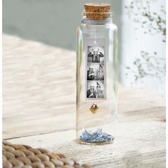 a glass bottle filled with photos on top of a wooden table