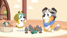 two cartoon dogs standing in front of a table with cupcakes and other items