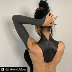 the back of a woman's body is covered in black paint and has her hands on her head