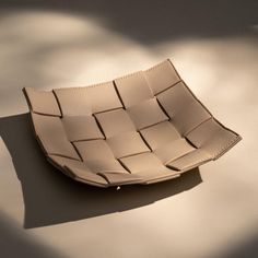 a white basket sitting on top of a table next to a shadow cast wall behind it