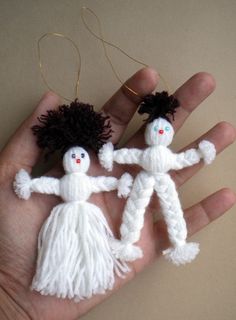 two small white dolls are being held by someone's hand