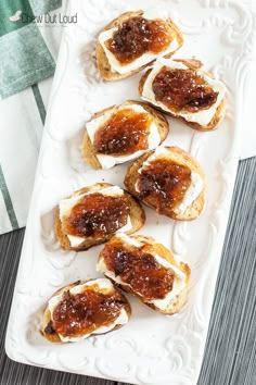 small pieces of bread with jam on them sitting on a white platter next to a towel