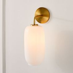 a wall light that is on the side of a white wall with a gold finish