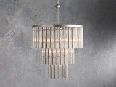 a chandelier hanging from the ceiling in a room with grey walls and concrete flooring