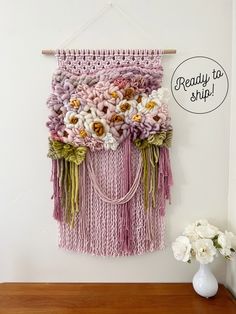 a wall hanging with flowers on it next to a vase