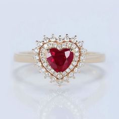 a red heart shaped diamond ring on a white background