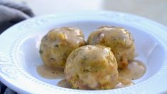 three meatballs covered in gravy on a white plate