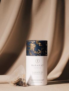 a canister with some tea next to it on a brown cloth covered tablecloth