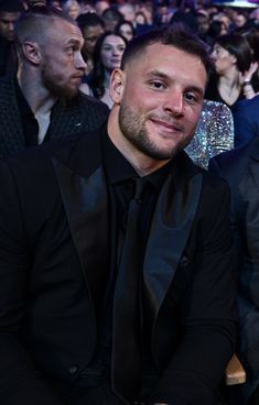 two men sitting next to each other in front of a large crowd at an event