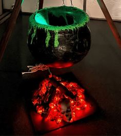 a large pot sitting on top of a wooden floor next to a fire pit with chains hanging from it's sides