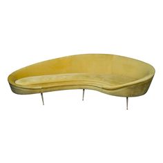 a curved yellow couch with metal legs