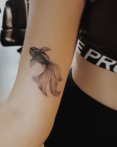 a woman's arm with a goldfish tattoo on the left side of her body