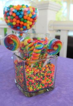 there are many candy candies in the glass container on the table and one is filled with lollipops