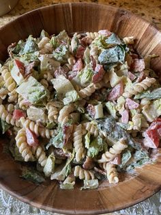 a wooden bowl filled with pasta salad on top of a table