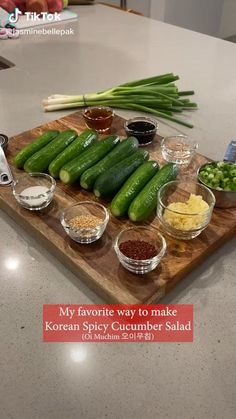 a wooden cutting board topped with cucumbers and seasoning on top of a counter