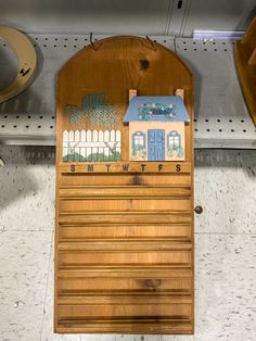 a wooden sign with a house painted on it's side in a store display