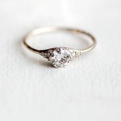 a gold ring with a diamond on it sitting on top of a white tablecloth