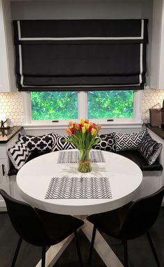 a white table with black and white pillows on it in front of a large window