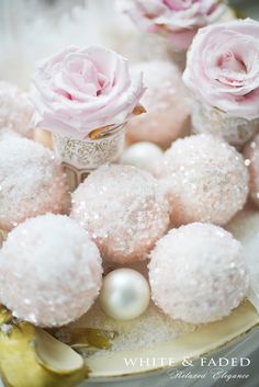 some white and pink desserts are on a plate with flowers in the background,