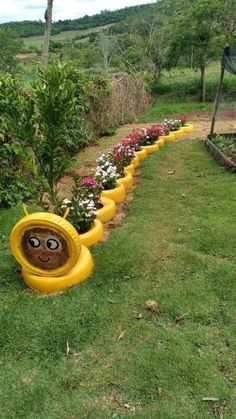 there is a garden with flowers and plants in the shape of a yellow tube that looks like a face