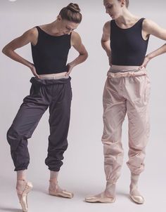 two women in ballet clothes standing next to each other with their hands on their hipss