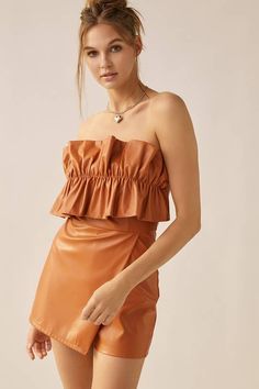 Fitted faux leather romper with tiered ruffled strapless top. Features flap skort and back zipper. Burnt orange in color Small: 0-2 Medium: 4-6 Large: 8-10 Chic Strapless Tube Top For Fall, Chic Brown Tube Top For Night Out, Ruffled Tube Top For Date Night In Spring, Spring Ruffled Tube Top For Date Night, Ruffled Tube Top For Date Night, Strapless Brown Tube Top For Night Out, Flirty Ruffled Tube Top For Date Night, Ruffled Bandeau Tube Top For Date Night, Maxi Romper