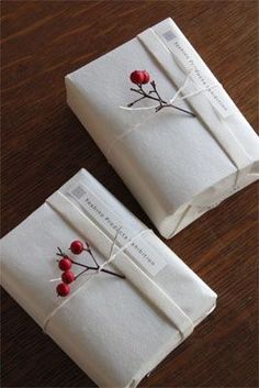 two wrapped packages with red berries on them sitting on top of a wooden table next to each other