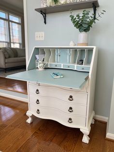 a white desk with a blue top and drawers in a living room next to a couch