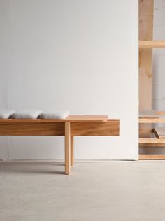 a wooden bench sitting in front of a white wall