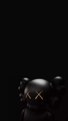 a small black toy with yellow eyes and two hands on it's head, standing in the dark