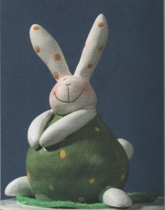 a stuffed rabbit sitting on top of a green pillow with polka dot dots around it's eyes