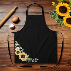 an apron with sunflowers painted on it next to eggs and other items for cooking