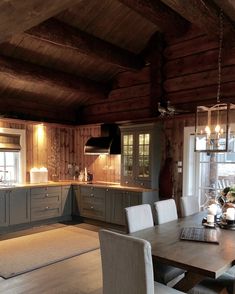 a dining room table and chairs in front of a kitchen with wood paneled walls