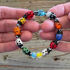 a hand holding a bracelet made out of glass beads with different colors and designs on it