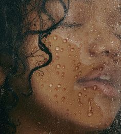 a woman's face is covered in water droplets as she looks out the window