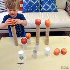 a young boy is playing with some apples