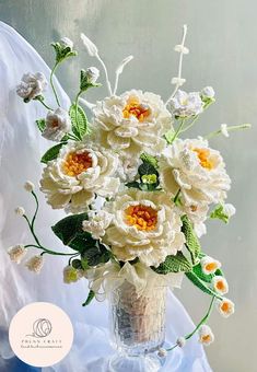 a vase filled with lots of white flowers on top of a blue cloth covered table