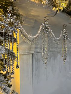 a bunch of beads hanging from the side of a white wall next to snow covered trees