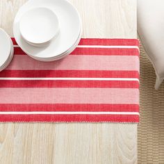 a place mat with red and white stripes is on the floor next to two plates