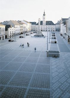 people are walking around an empty square in the middle of town